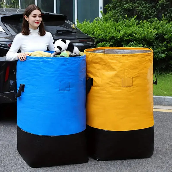 A woman stands next to two large waterproof storage bags, one blue and one yellow, outdoors.