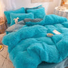 A bright turquoise plush mink velvet duvet set with matching pillows and a gray blanket on a bed.