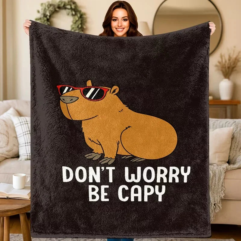 A dark gray plush flannel blanket featuring a cartoon drawing of a bear wearing sunglasses with the text Don't Worry Be Capy