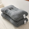 A gray ergonomic contour neck pillow with a honeycomb pattern is shown resting on a light-colored fabric.