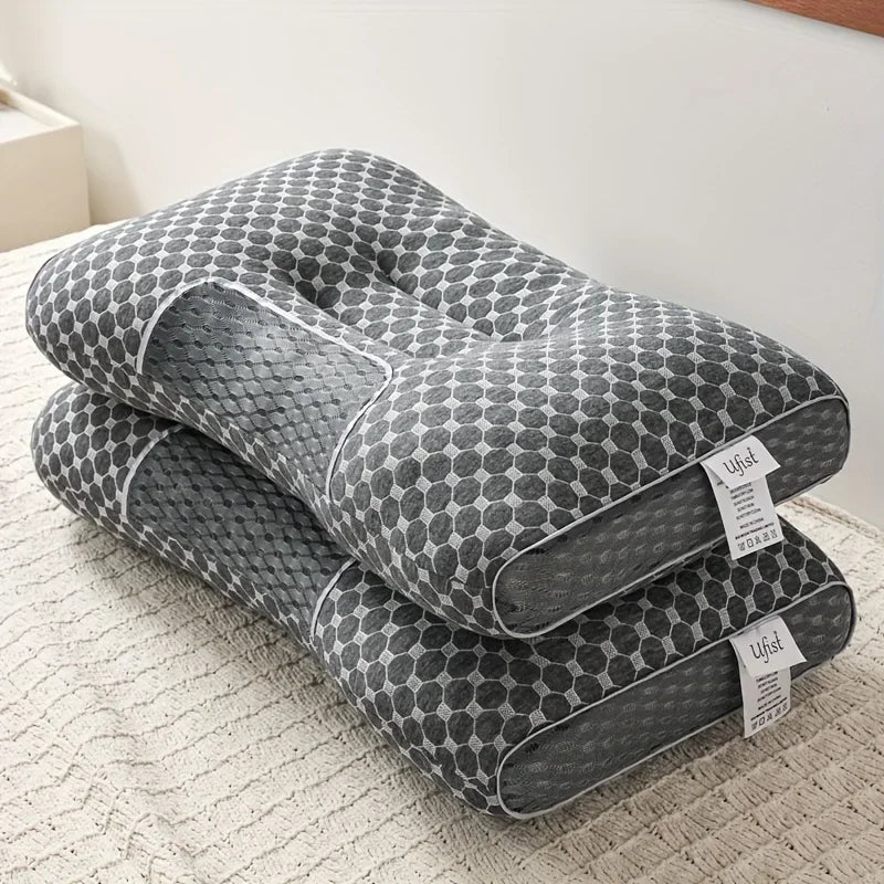 A gray ergonomic contour neck pillow with a honeycomb pattern is shown resting on a light-colored fabric.