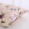 A light pink silk pillowcase with a purple floral print and a zipper opening is shown.