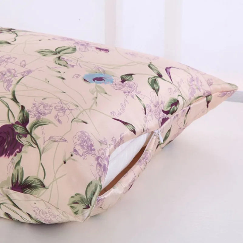 A light pink silk pillowcase with a purple floral print and a zipper opening is shown.