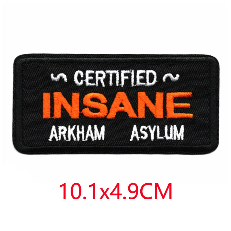 Black iron-on embroidered letter patch with the text Certified Insane Arkham Asylum in orange and white.