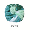 A ball of hand-woven chunky chenille yarn in shades of teal and light green.