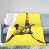 A yellow throw blanket featuring a graphic of a soccer player kicking a ball.