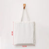 A white canvas tote bag with wooden handles is displayed against a white background.