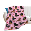 A pink flannel blanket featuring a repeating pattern of black and tan dachshund dogs.