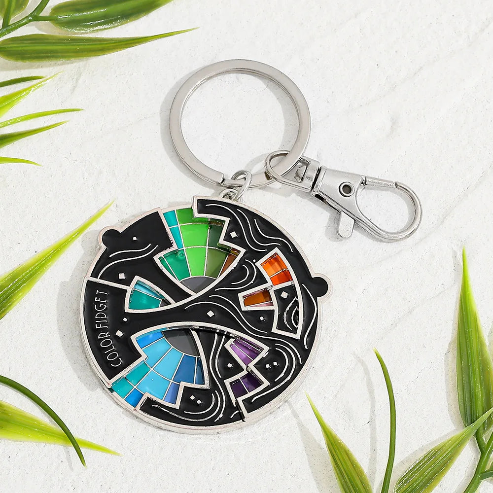 An enamel pin keychain featuring a colorful color wheel design on a black background.