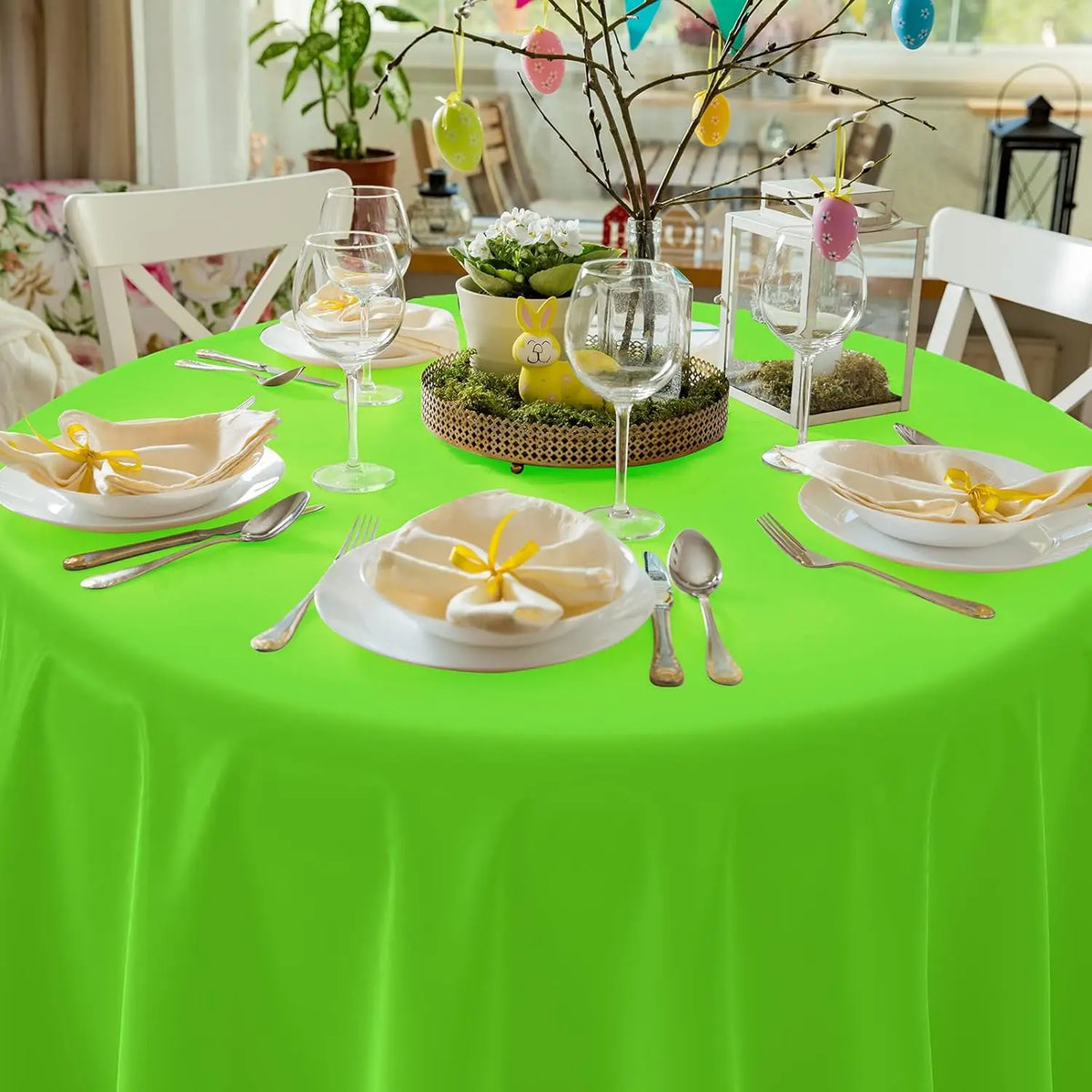 A bright green plastic disposable table cover set for a dining table with yellow floral accents and glassware.