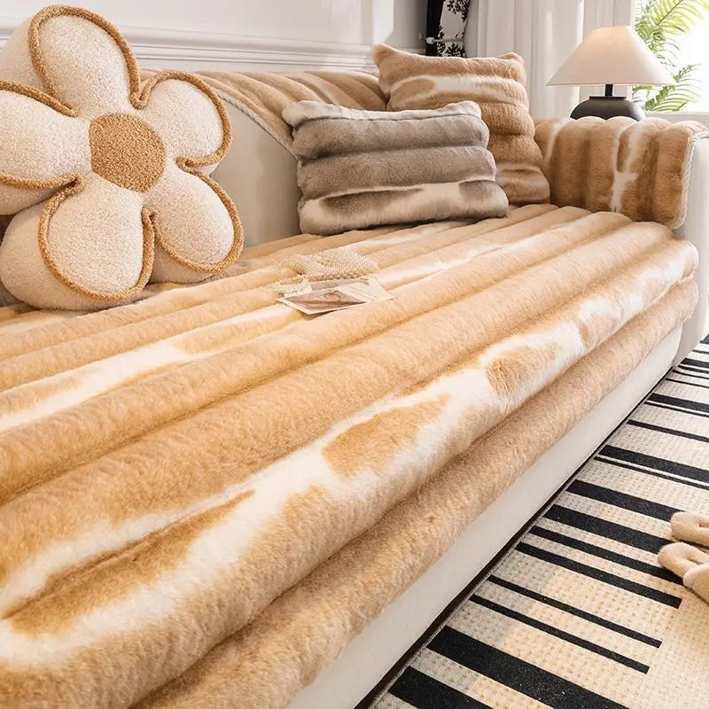 A beige plush velvet sofa protector cover with a cow print pattern and matching throw pillows.