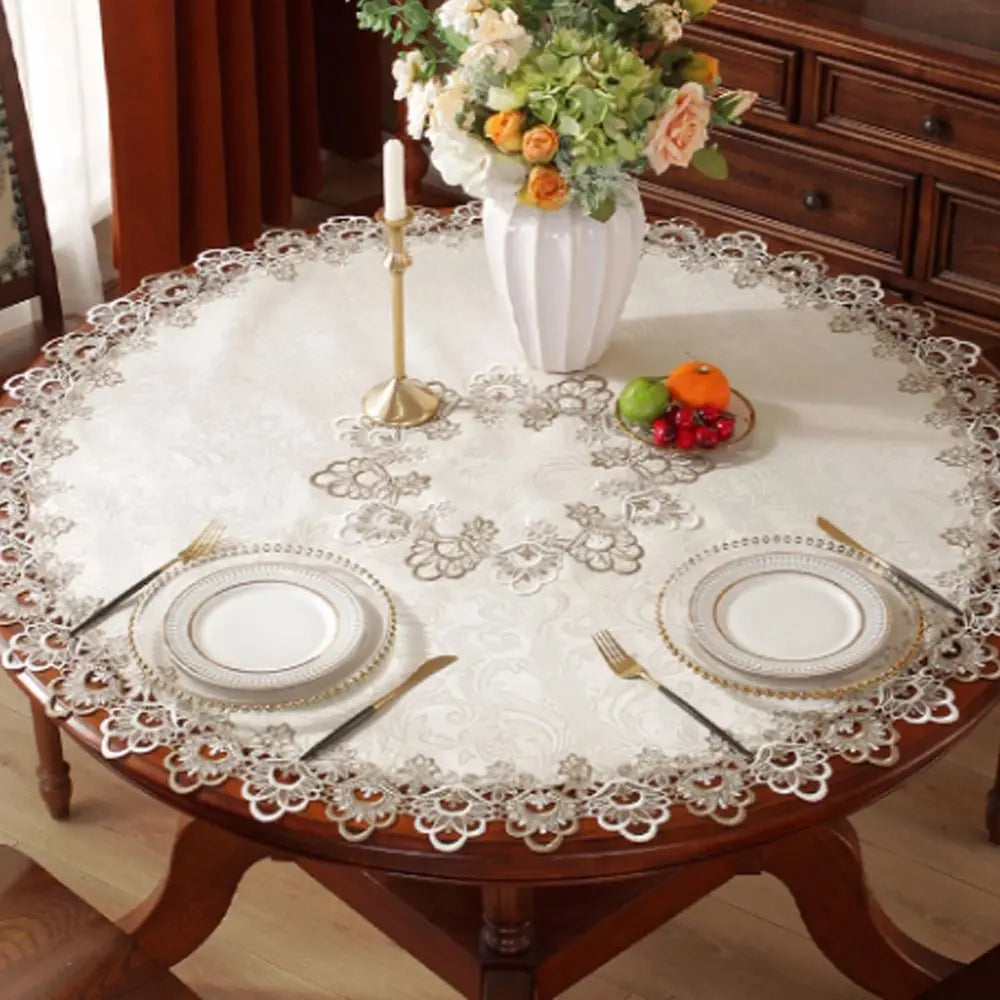 Elegant lace-trimmed round tablecloth set for a dining table with floral centerpiece and fruit