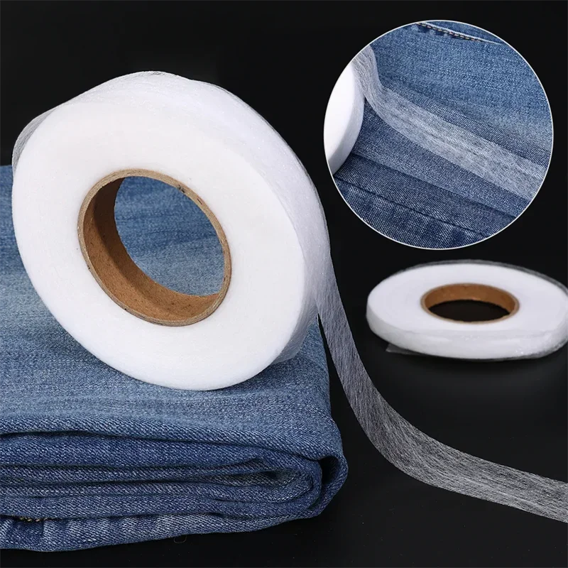 Roll of white double-sided iron-on adhesive tape next to a folded denim fabric and a circular view of the tape.