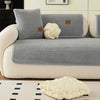 A light gray sofa with matching throw pillows and a white knitted decorative object on the floor.