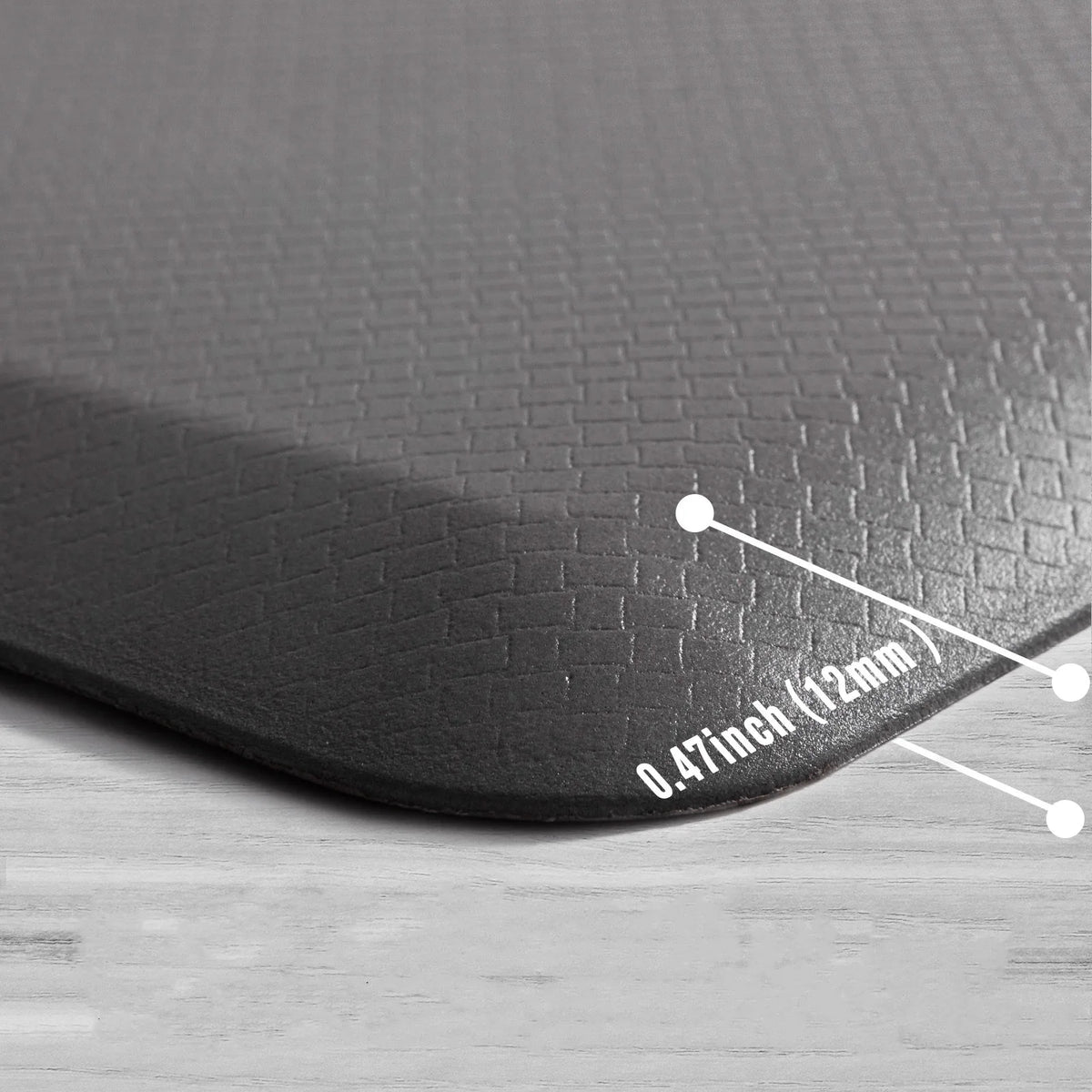 A close-up view of a black anti-fatigue PVC kitchen mat showing its thickness measurement.