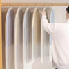 A person is hanging a transparent zippered clothes storage bag on a wooden rack.