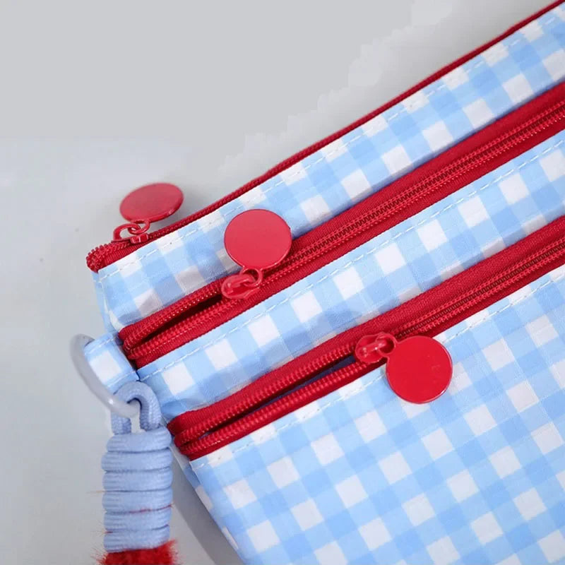 A close-up of a blue and white checkered waterproof passport holder with red zippers and decorative red buttons.