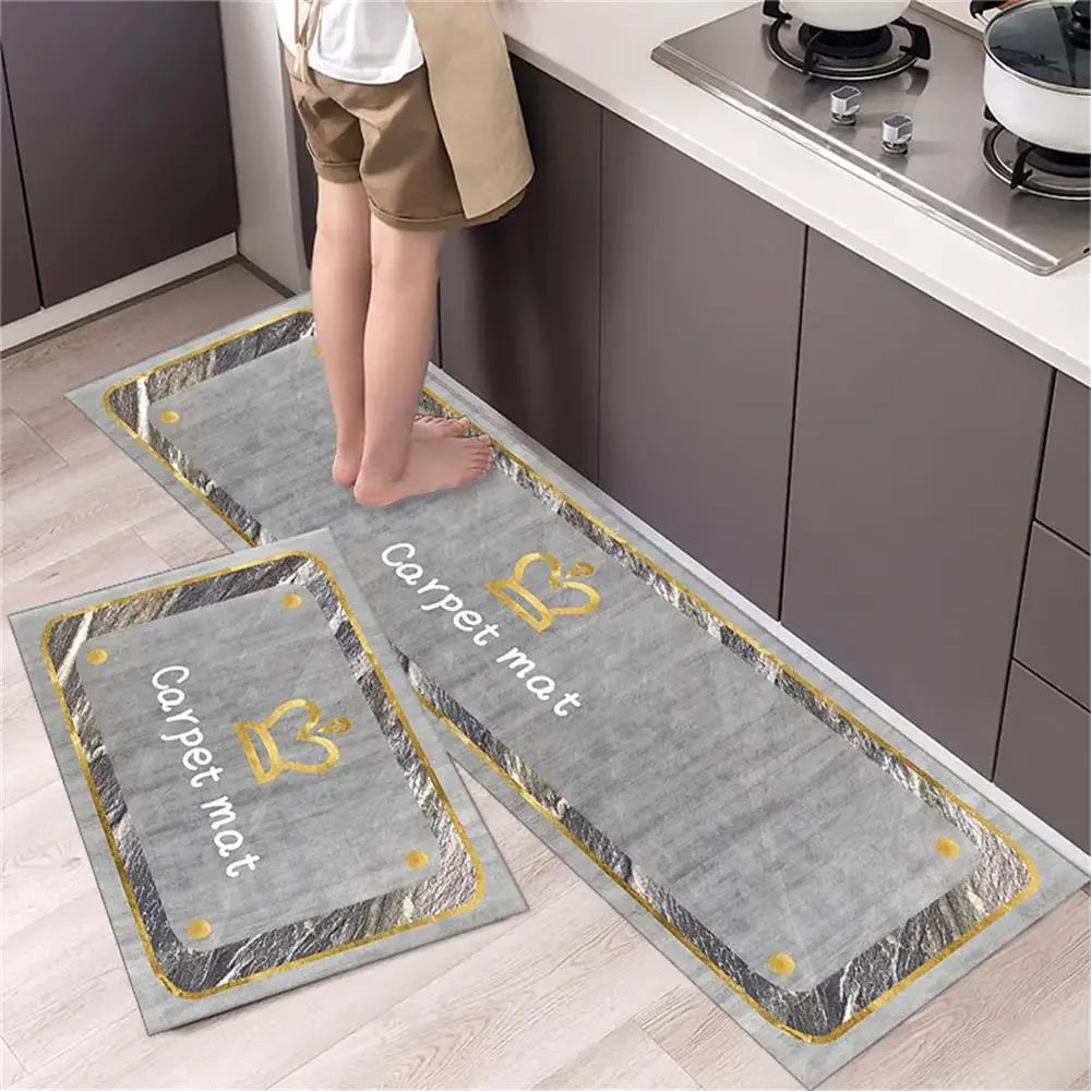 Two rectangular gray non-slip waterproof kitchen mats with a gold diamond print placed on a light wood floor.