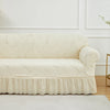 A cream jacquard stretch sofa cover featuring a leaf pattern displayed on a white sofa.