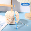 A blue ergonomic crochet hook with a thin wire is shown next to a ball of light pink yarn.