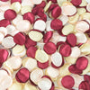 A close-up view of a pack of 100 silk rose petals in shades of dusty pink, cream, and deep burgundy.