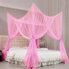 Pink sheer mosquito net curtain draped over a bed frame