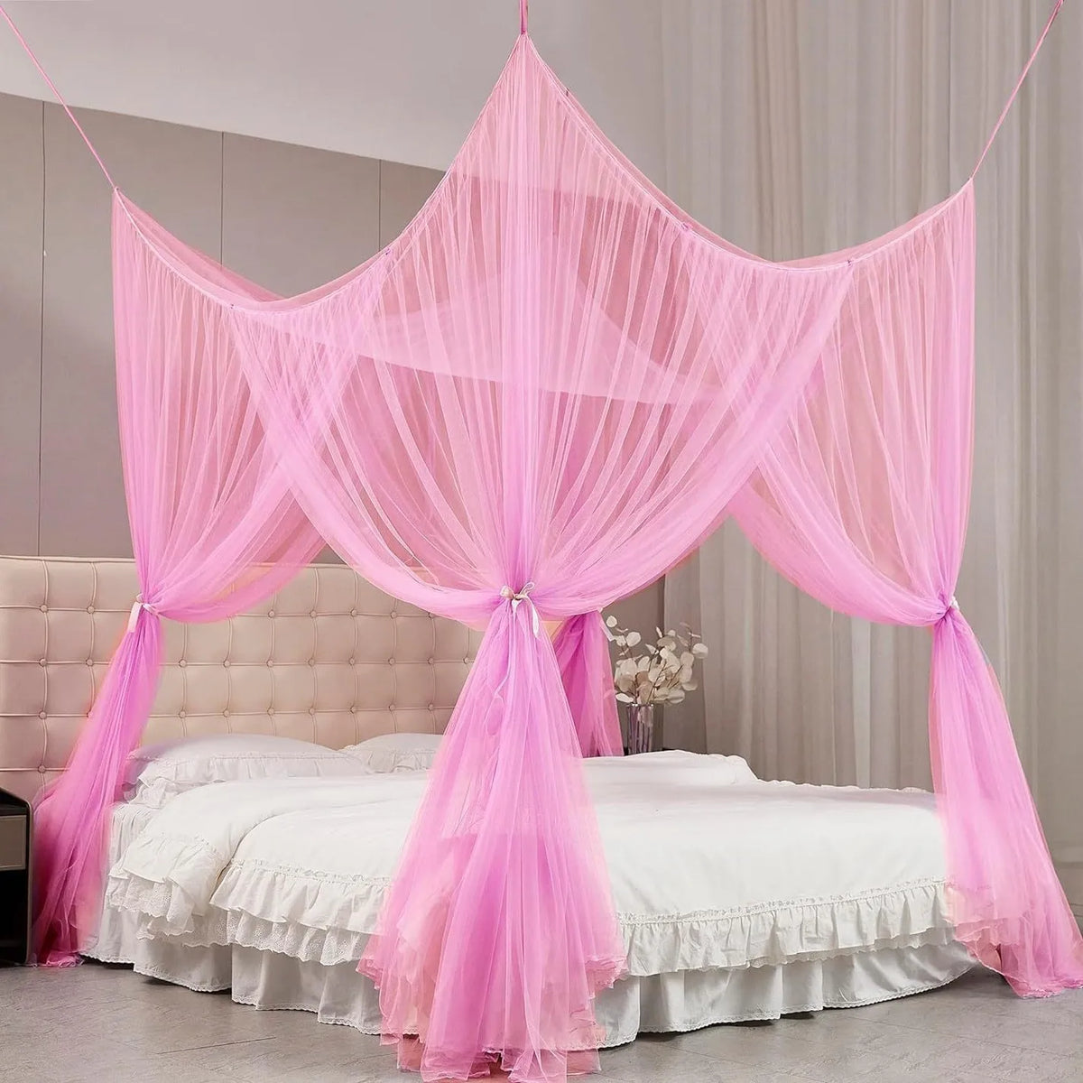 Pink sheer mosquito net curtain draped over a bed frame