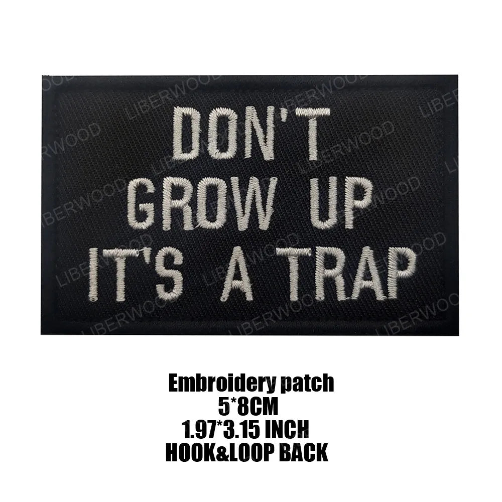 Black embroidered patch with white text that reads Don't Grow Up It's a Trap