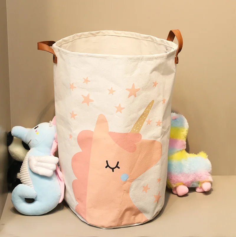 A white storage basket with a pink unicorn design and star accents, featuring a natural fiber material.