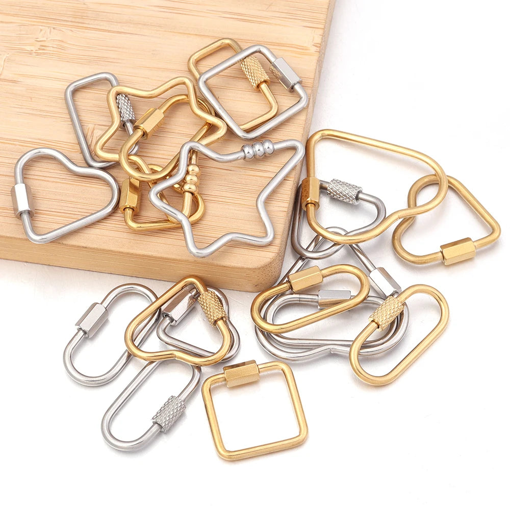 A collection of gold and silver heart-shaped screw lock carabiner clasps for jewelry making displayed on a wooden surface.