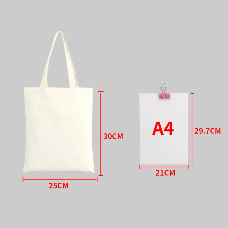 A white canvas tote bag with handles shown next to an A4 sized piece of paper.