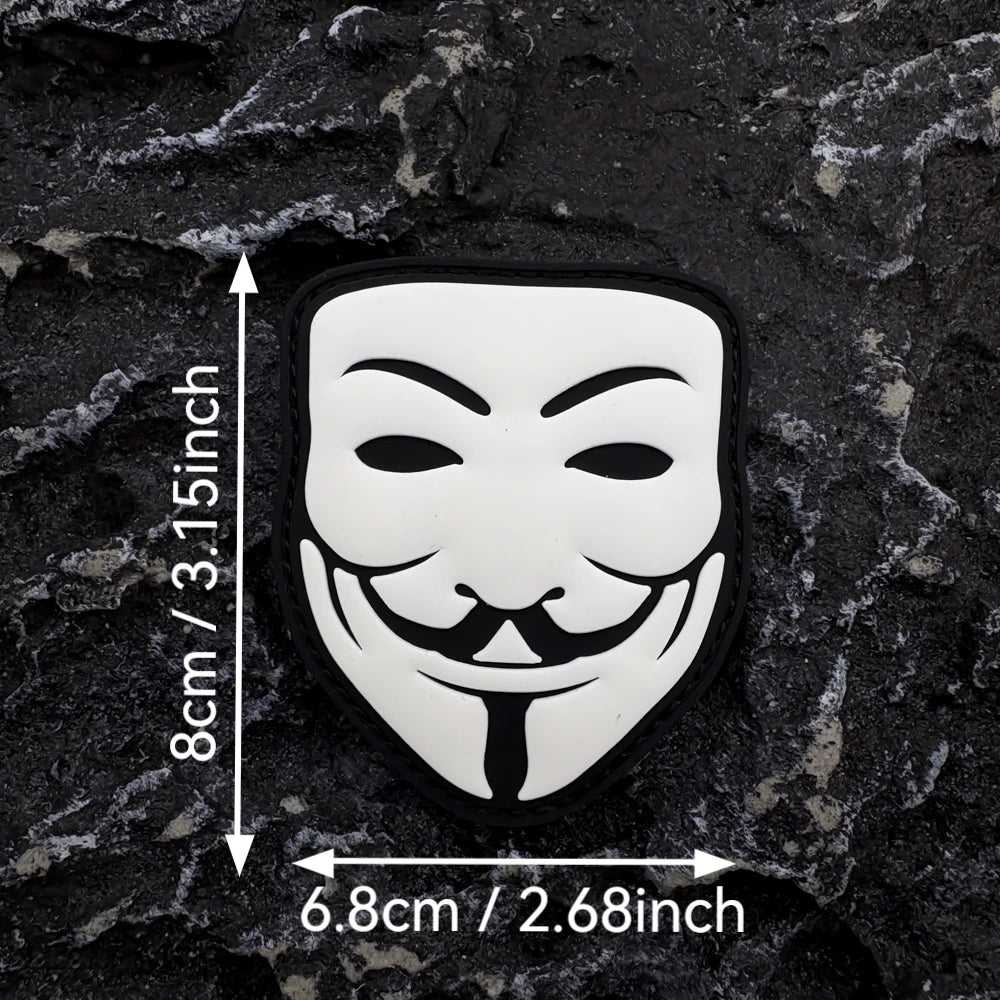 A black embroidered patch of a white smiley face with a black mustache and tie, featuring a glow-in-the-dark design.