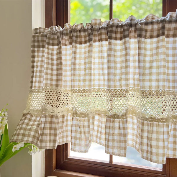 Beige gingham crochet lace curtain valance hanging in a window frame.