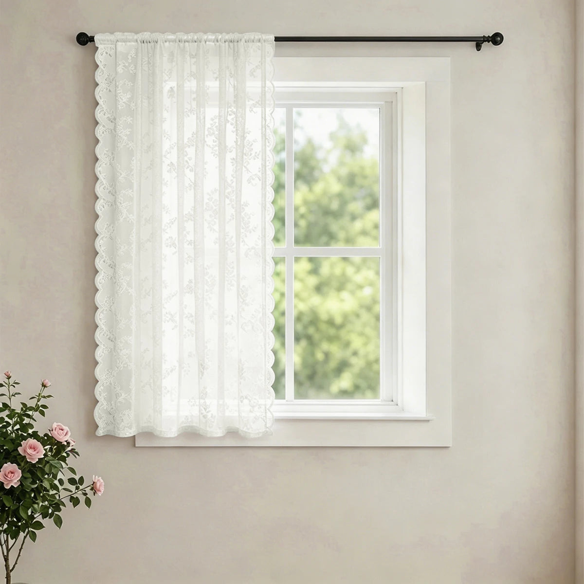 White vintage French-style lace curtain with a delicate wave border hanging in a window.