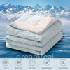 A stack of white and beige reversible cooling quilts with icons indicating features like cool, breathable, silky soft, hypoal