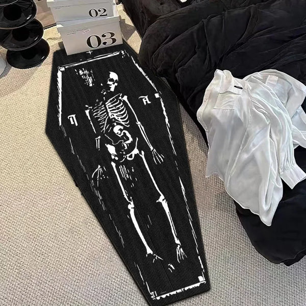 A black floor mat featuring a white silhouette of a gothic skull and skeleton design.
