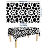Black and white cow print disposable plastic tablecloth displayed on a wooden table.