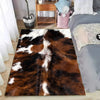 A brown and white faux cowhide pattern area rug placed on a wooden floor.