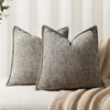 A close-up of a textured gray chenille throw pillow resting on a light-colored sofa or blanket.