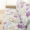 A floral print elastic sofa protective cover featuring purple and green leaves on a light background.