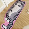 A pink decorative cat mat featuring a gray and white striped cat design placed on a wooden floor.