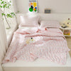 A pink floral quilt set featuring a duvet, pillow, and blanket displayed on a white shelf.
