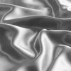 Close-up shot of two satin pillowcases draped and folded in a smooth, reflective gray fabric.