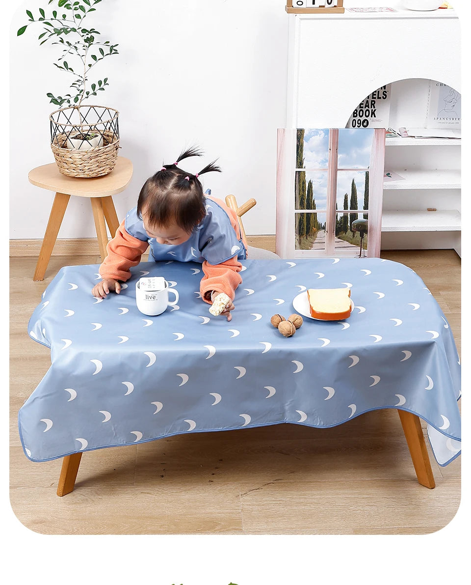 A baby is playing on a light blue waterproof play mat with anti-slip backing, featuring a design of crescent moons.
