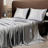 A luxury solid satin bedding set featuring silver gray sheets and pillows on a bed.