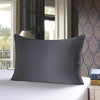 A solid gray silk pillowcase resting on a white bed in a well-lit room.