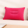 A bright pink inflatable travel neck pillow resting on a light-colored surface.