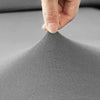 A hand is touching a gray fabric sofa cushion slipcover.