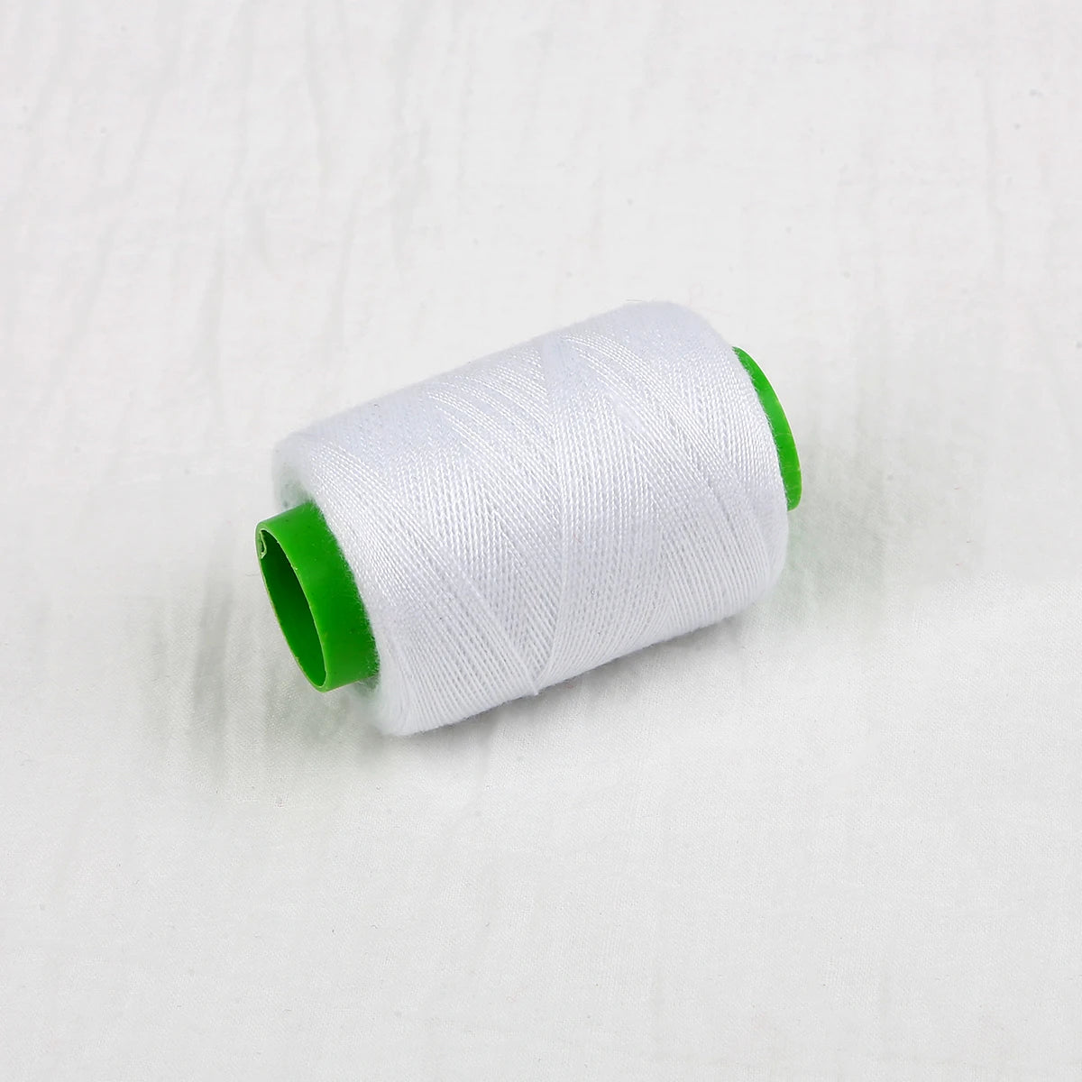 A roll of white sewing thread with a green core.