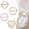 A set of elegant gold-toned metal clips and a pearl bracelet displayed against a white fabric background.